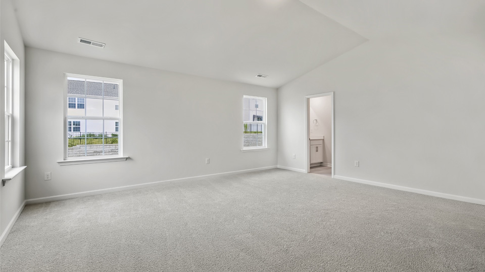 primary bedroom with two windows and carpeting, attached bath