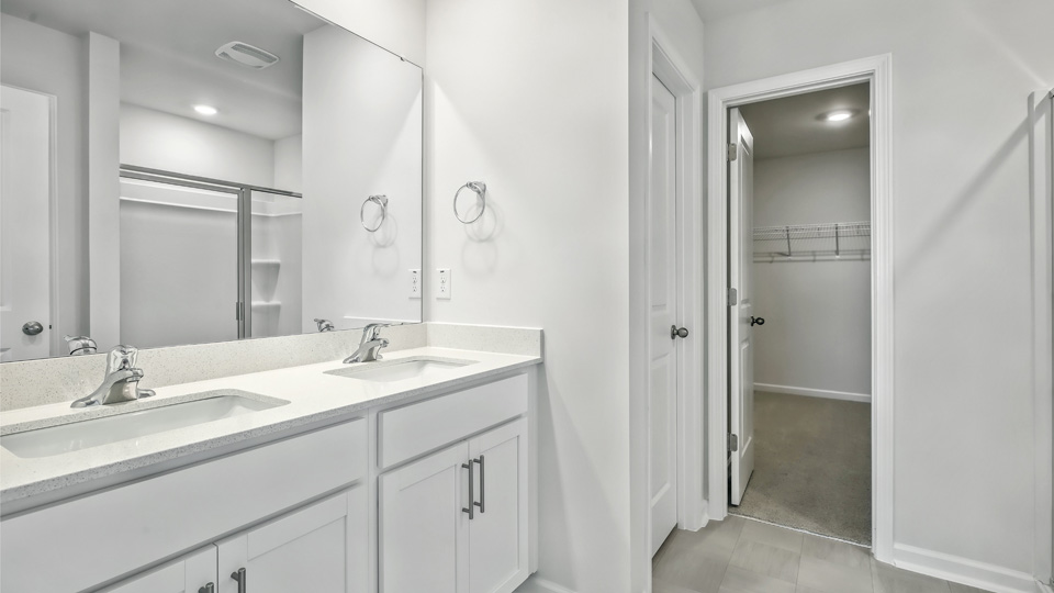 primary bathroom with walk in shower and dual vanity sinks