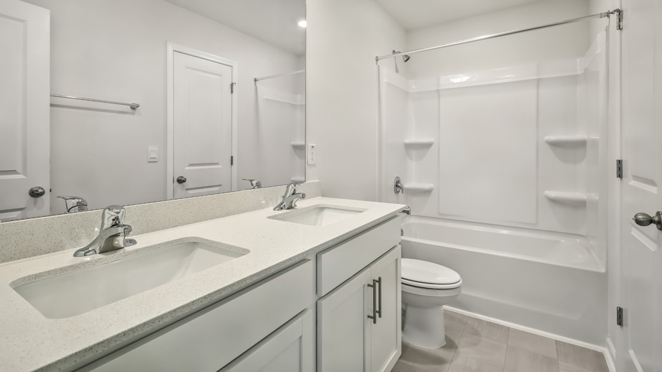 secondary bathroom with shower tub combo and dual vanity sink