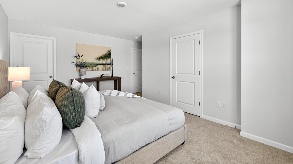primary bedroom with two windows and carpeting, attached bath