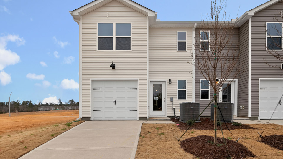 Two story town home with yellow siding & garage