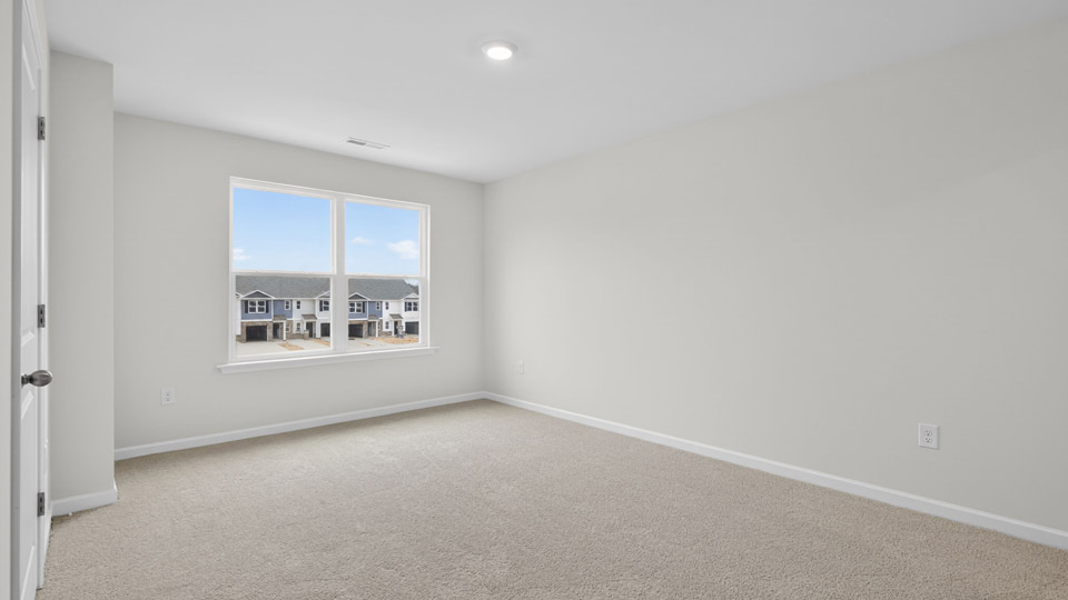 Primary bedroom with carpet floors and windows with access to the primary bathroom