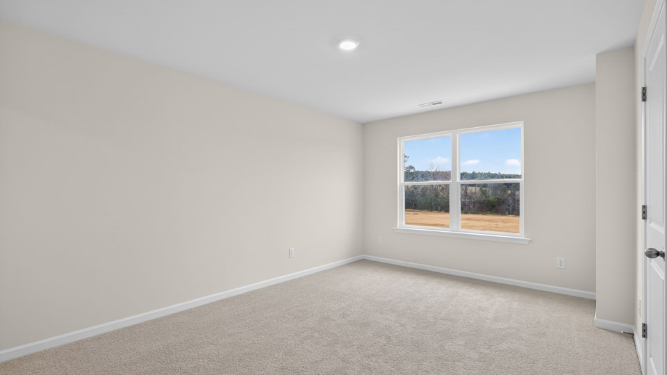 Primary bedroom with carpet floors and windows with access to the primary bathroom
