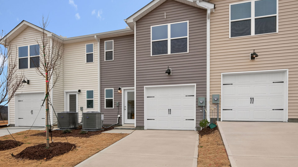 Two story town home with brown siding with garage