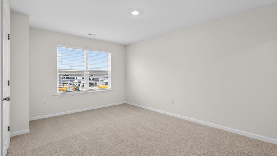 Primary bedroom with carpet floors and windows with access to the primary bathroom