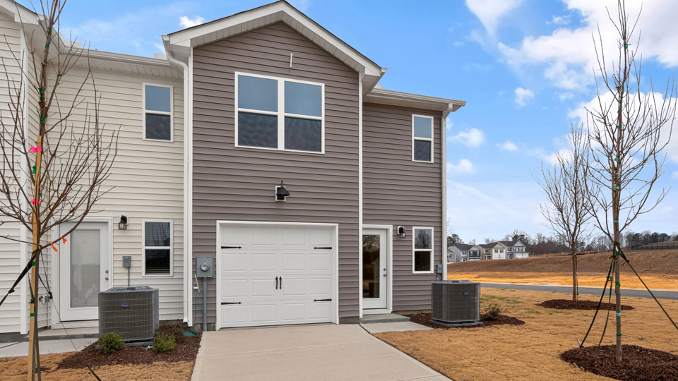 Two story town home with brown siding & garage