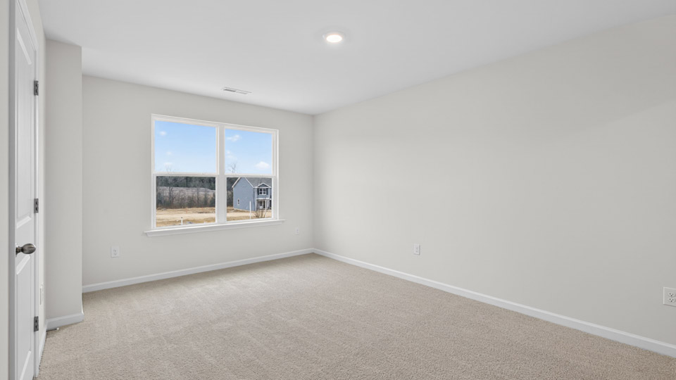 Primary bedroom with carpet floors and windows with access to the primary bathroom