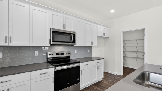 kitchen with white cabinets tile backsplash and quartz countertops