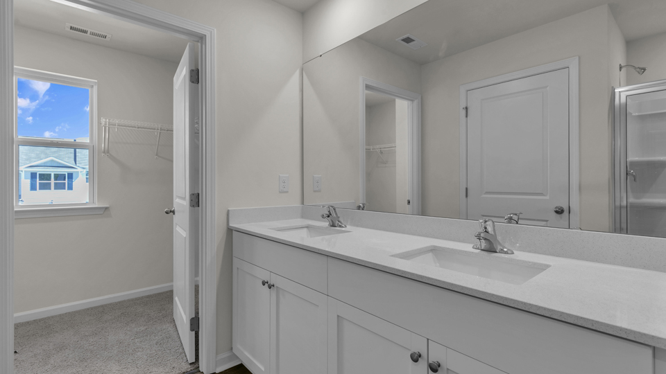 primary bathroom with walk in shower and dual vanity sinks
