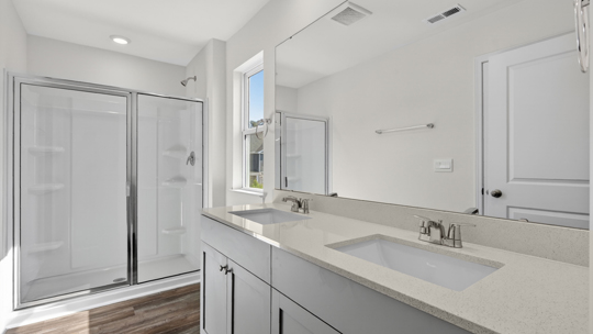 bathroom with dual vanity sinks gray cabinets and walkin glass door shower