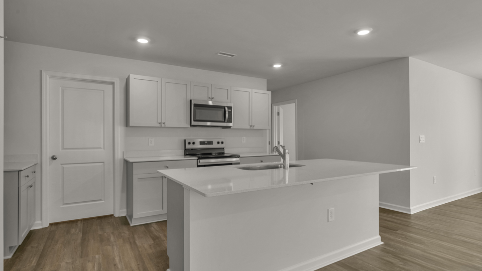 kitchen with quartz counters, kitchen island, pantry, stainless steel appliances