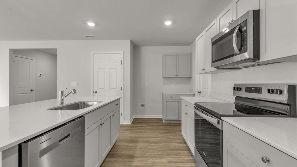 kitchen with quartz counters, kitchen island, pantry, stainless steel appliances