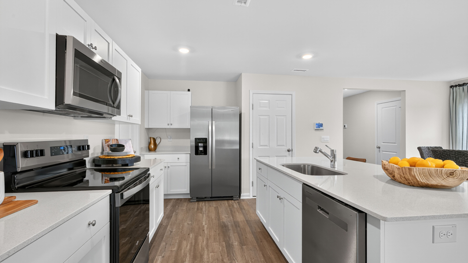 kitchen with quartz counters, kitchen island, pantry, stainless steel appliances