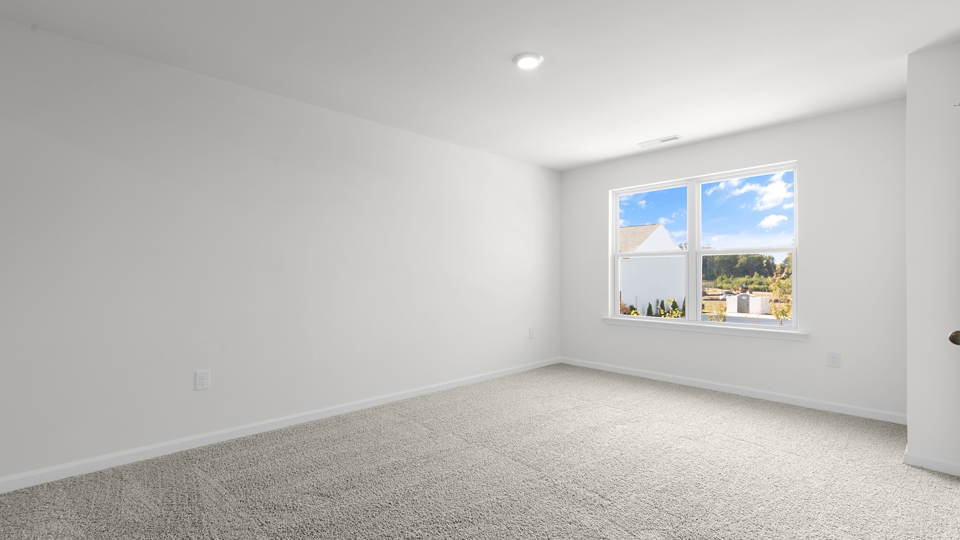 primary bedroom with two windows and carpeting, attached bath