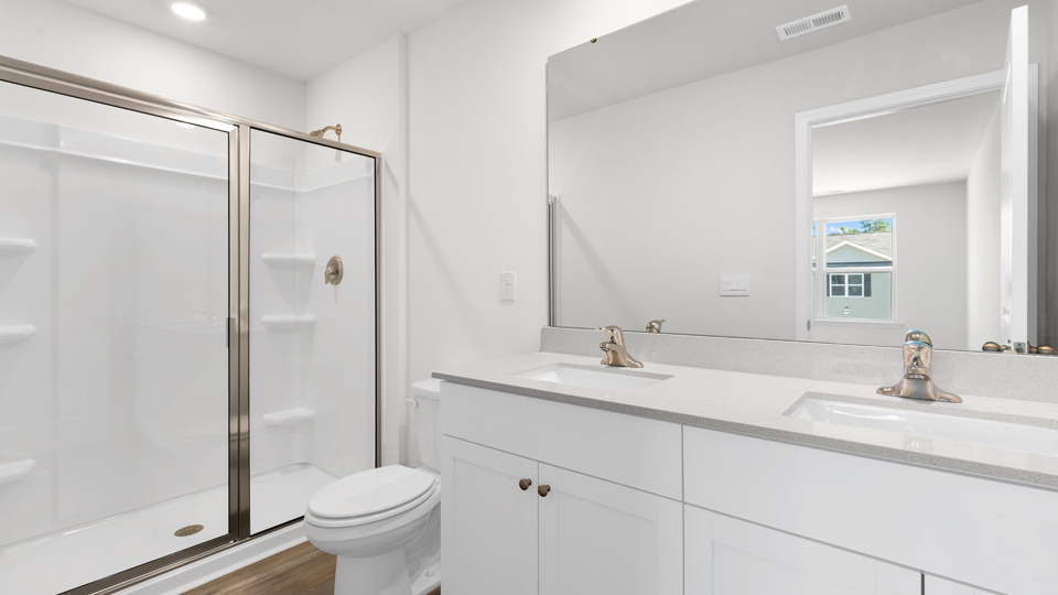 primary bathroom with walk in shower and dual vanity sinks