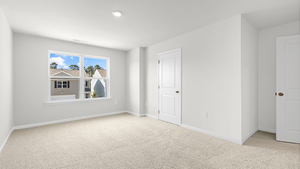 primary bedroom with two windows and carpeting, attached bath
