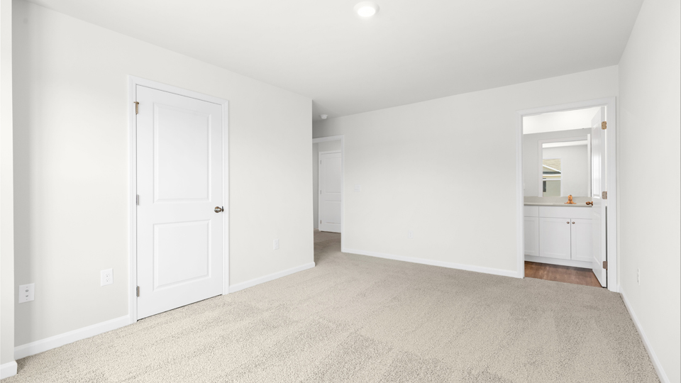 primary bedroom with two windows and carpeting, attached bath