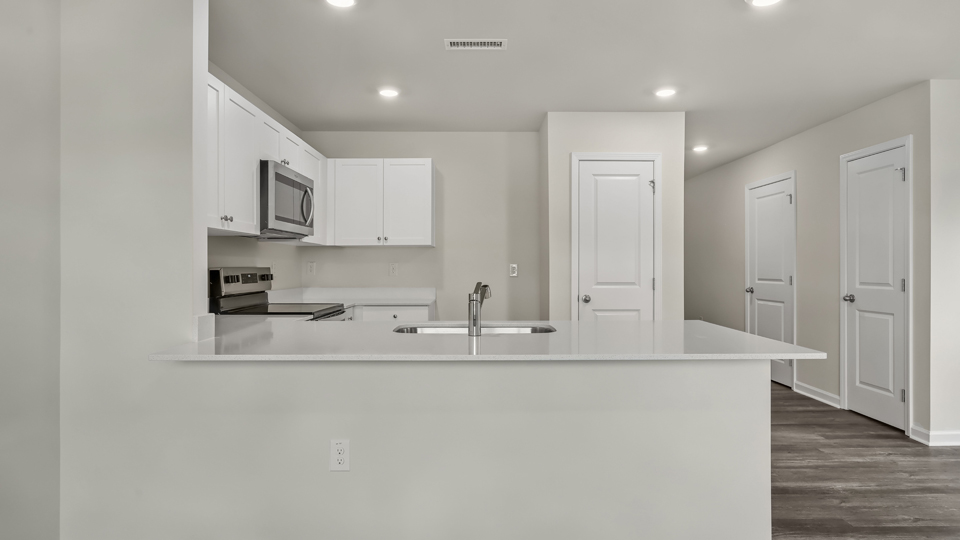 kitchen with quartz counters, kitchen island, pantry, stainless steel appliances
