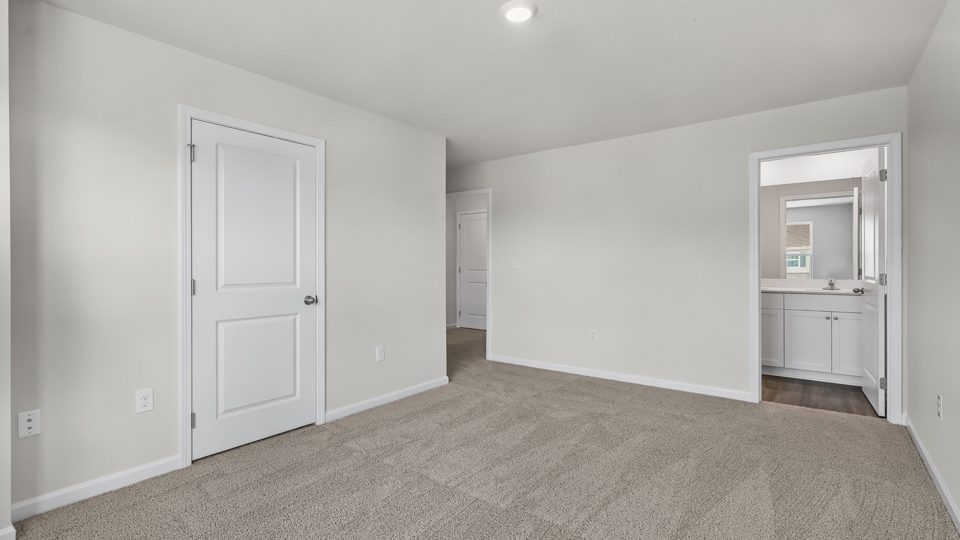 primary bedroom with two windows and carpeting, attached bath