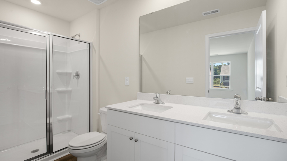 primary bathroom with walk in shower and dual vanity sinks