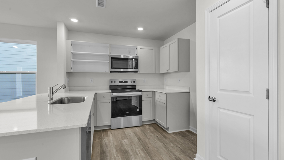 kitchen with quartz counters, kitchen island, pantry, stainless steel appliances
