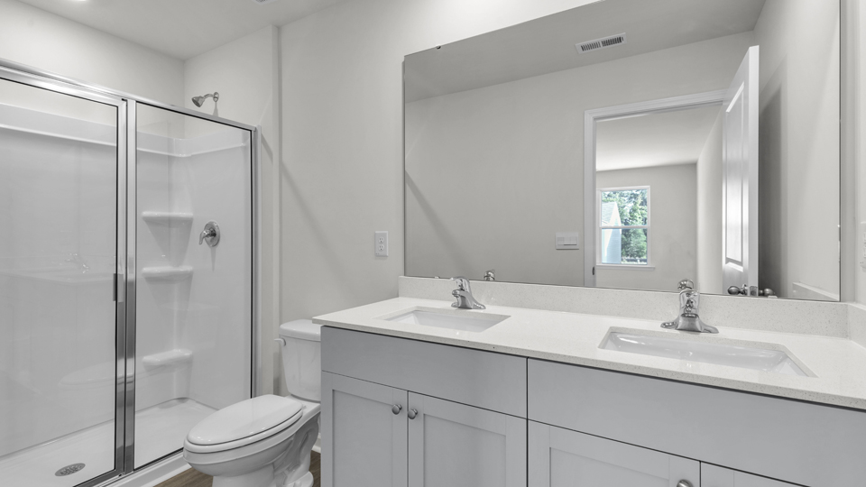 primary bathroom with walk in shower and dual vanity sinks