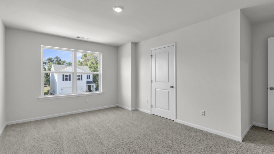 primary bedroom with two windows and carpeting, attached bath