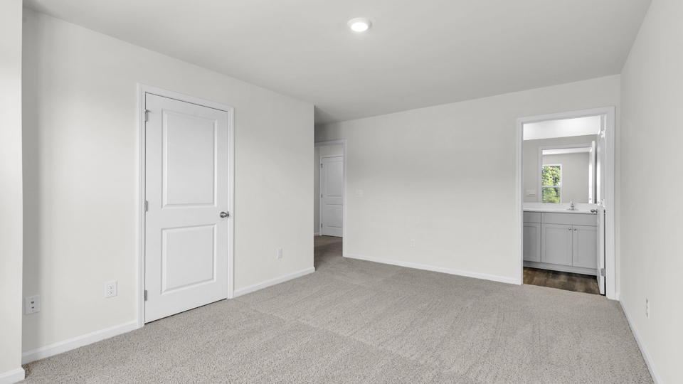primary bedroom with two windows and carpeting, attached bath