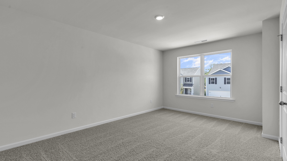 primary bedroom with two windows and carpeting, attached bath