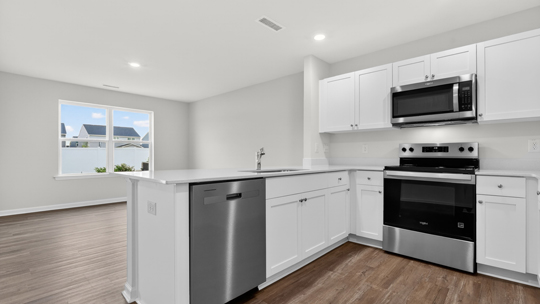kitchen with quartz counters, kitchen peninsula, pantry, stainless steel appliances