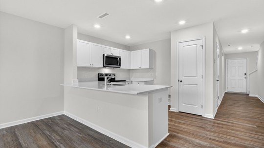 kitchen with quartz counters, kitchen peninsula, pantry, stainless steel appliances