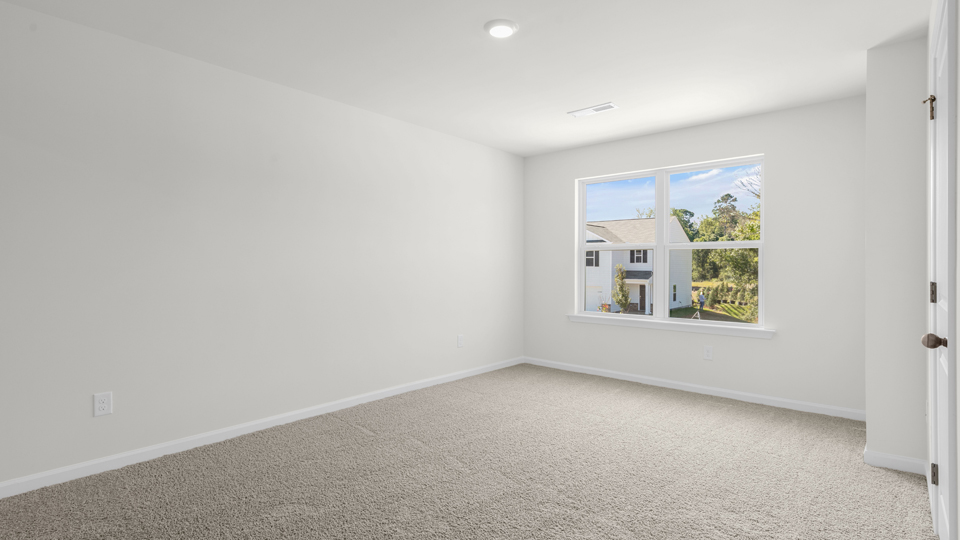 primary bedroom with two windows and carpeting, attached bath