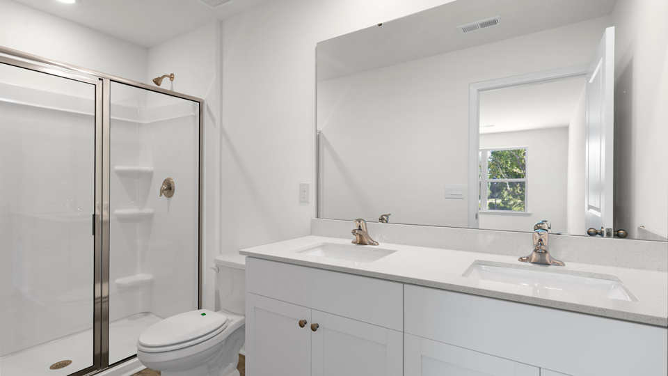 primary bathroom with walk in shower and dual vanity sinks