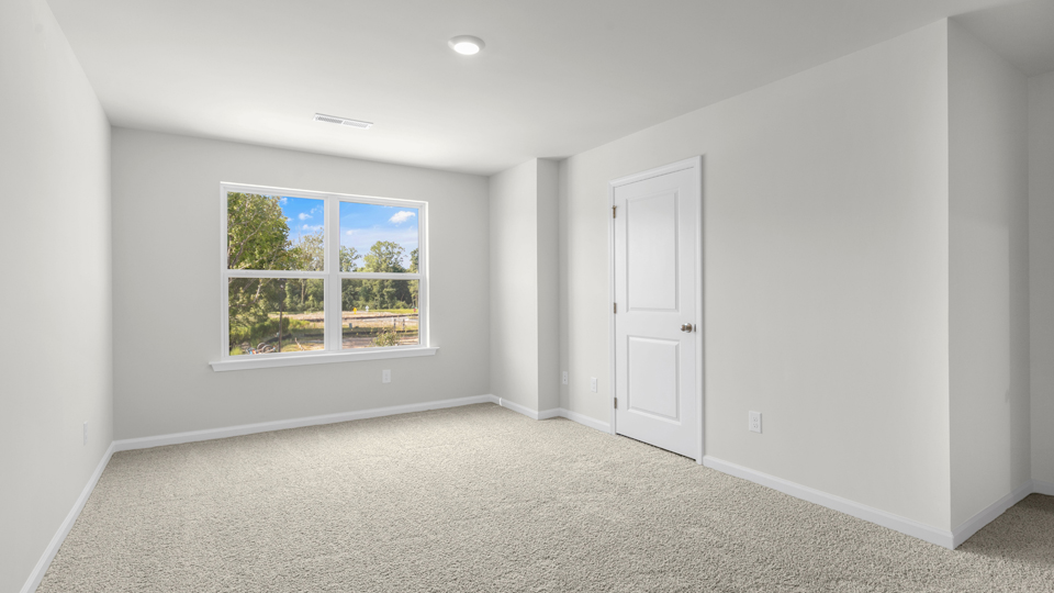 primary bedroom with two windows and carpeting, attached bath