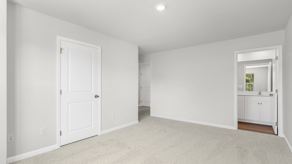primary bedroom with two windows and carpeting, attached bath