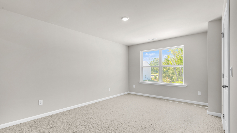 primary bedroom with two windows and carpeting, attached bath