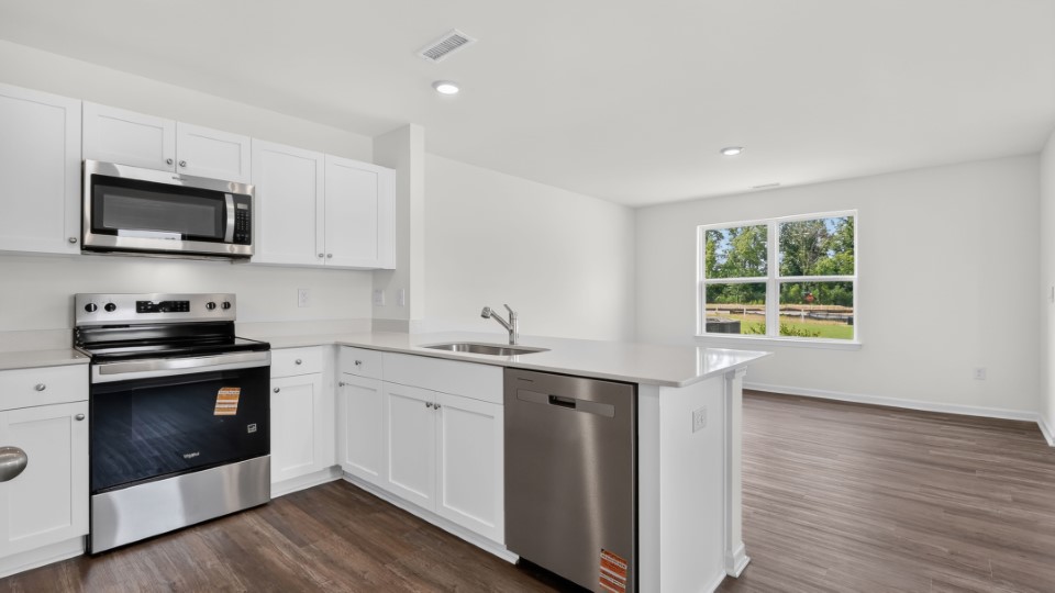 kitchen with quartz counters, kitchen peninsula, pantry, stainless steel appliances