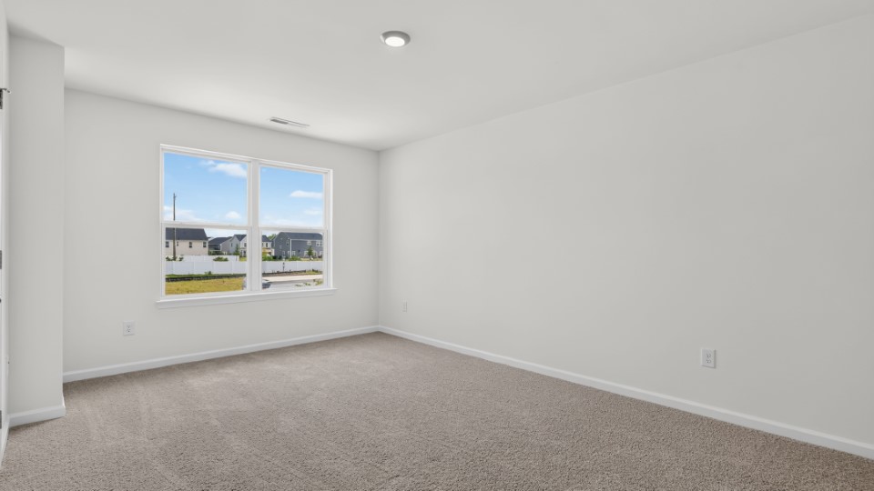 primary bedroom with two windows and carpeting, attached bath
