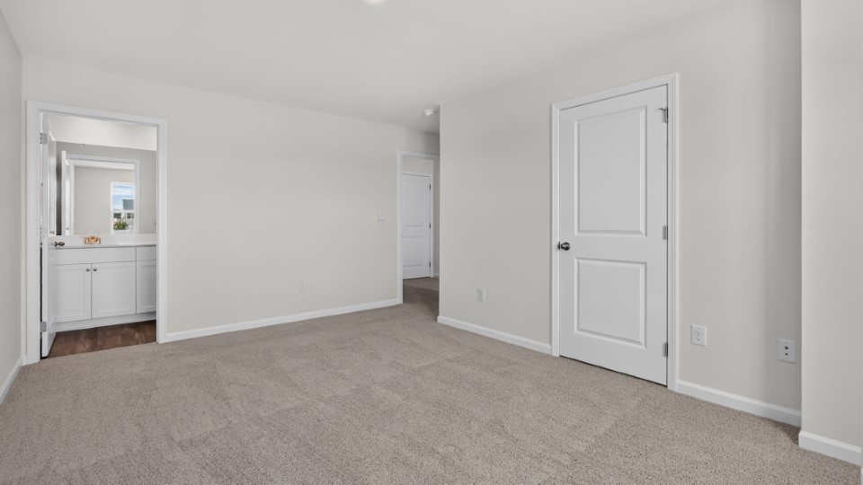 primary bedroom with two windows and carpeting, attached bath