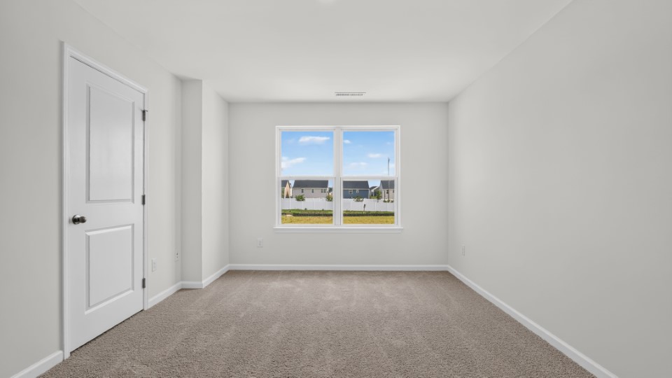 primary bedroom with two windows and carpeting, attached bath