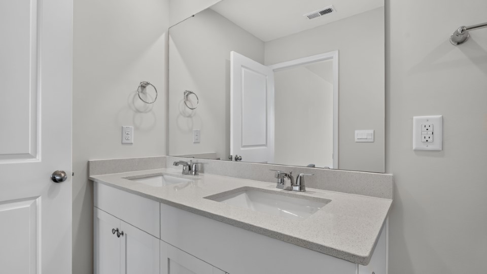 primary bathroom with walk in shower and dual vanity sinks