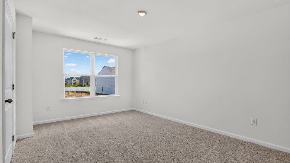 primary bedroom with two windows and carpeting, attached bath