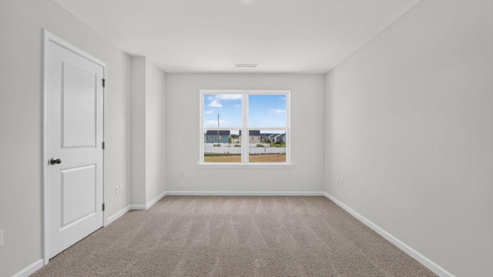 primary bedroom with two windows and carpeting, attached bath