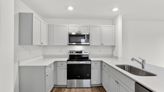 kitchen with quartz counters, kitchen peninsula, pantry, stainless steel appliances