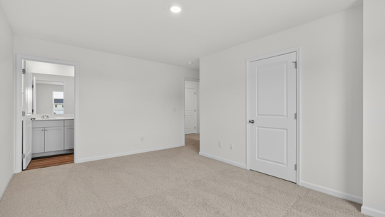 primary bedroom with two windows and carpeting, attached bath