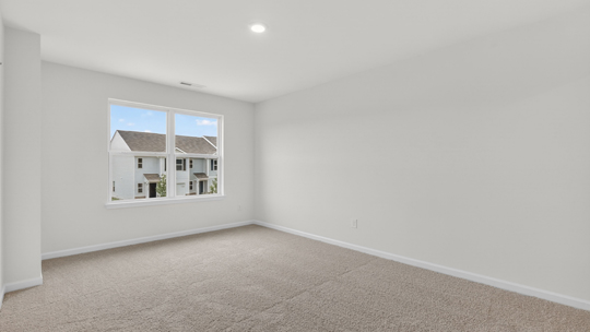 primary bedroom with two windows and carpeting, attached bath