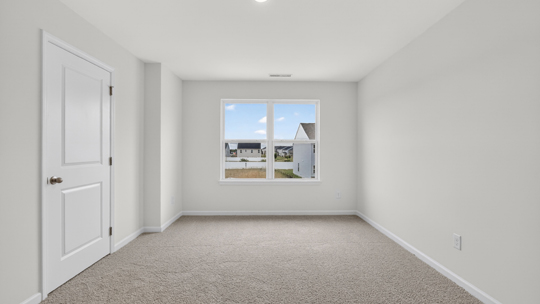 primary bedroom with two windows and carpeting, attached bath