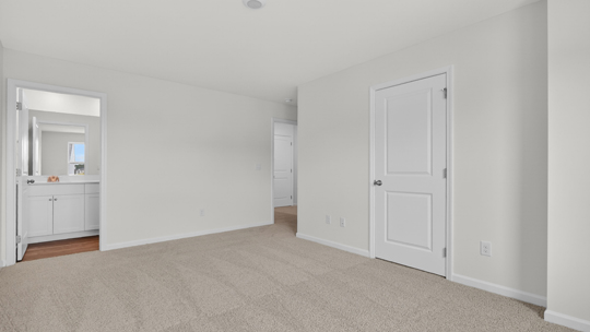 primary bedroom with two windows and carpeting, attached bath