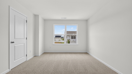 primary bedroom with two windows and carpeting, attached bath