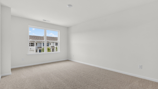 primary bedroom with two windows and carpeting, attached bath